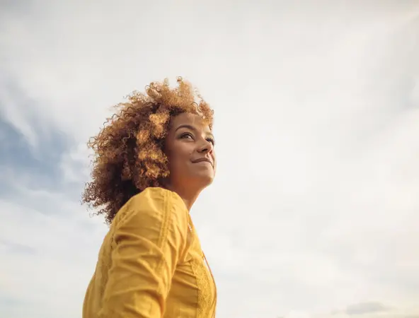 Woman in yellow top with grey clouds in background