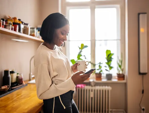 Woman in kitchen on phone with cup