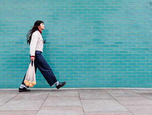 Woman with shopping walking in front of turquoise wall