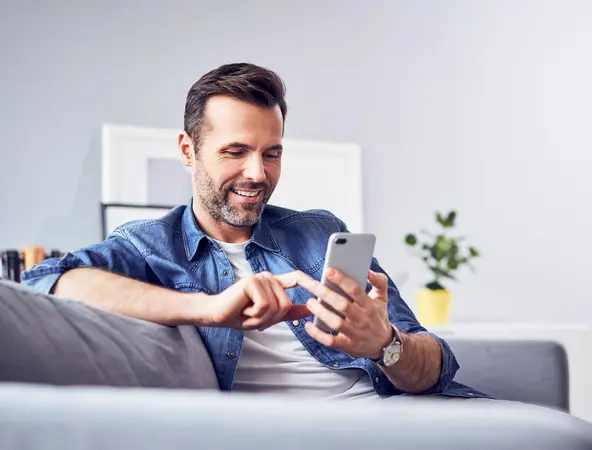 Man sitting on couch using phone
