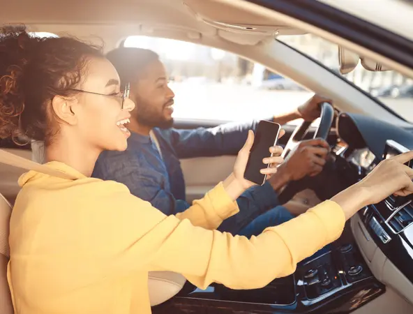 man driving with his wife on passenger seat. She is indicating the road to take. 