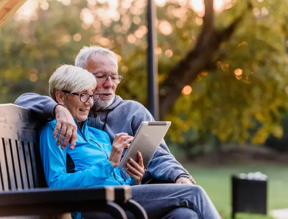 old couple on a bench looking at their tablet