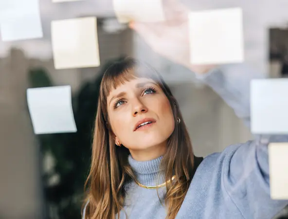 woman adding post it note on a wall