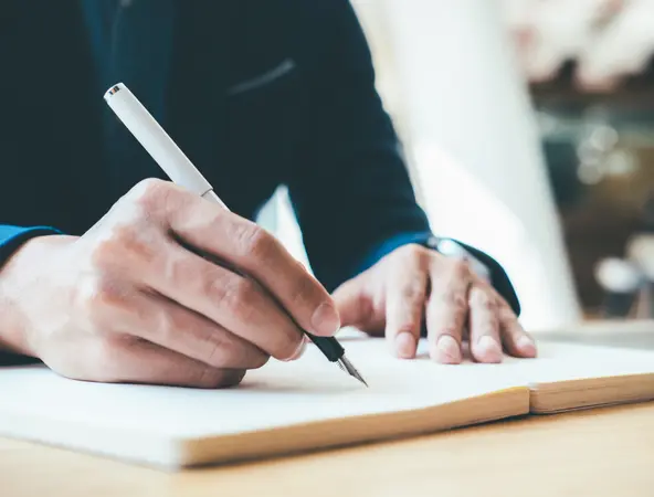 Une homme écrit dans un cahier