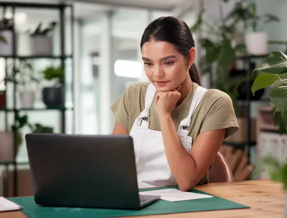 ragazza seduta al desk che guarda schermo laptop