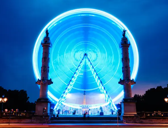 foto frontale di una ruota panoramica in movimento illuminata di azzurro