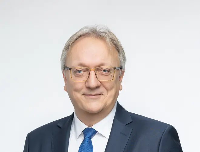 Professional asset manager in a suit, in the Amundi offices with a neutral background.