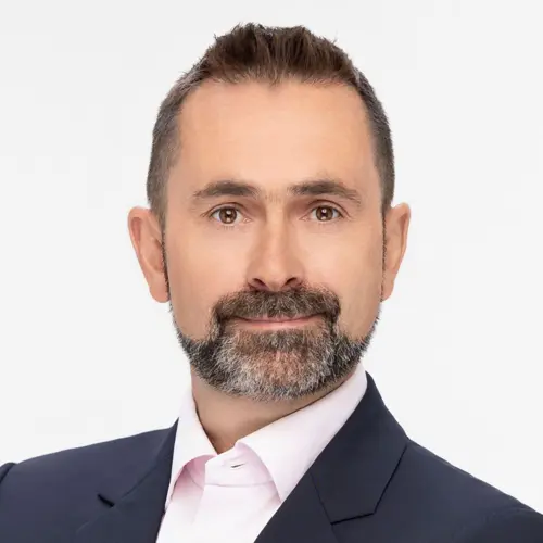 A smiling financial expert in a suit, set against a plain background.