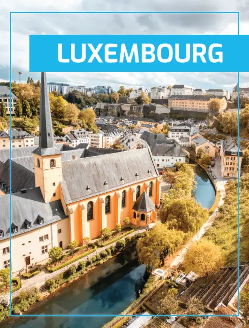 Scenic view of Luxembourg with a river, buildings, and autumn foliage.