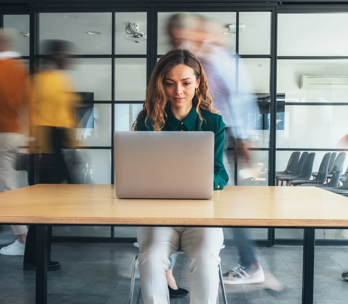 A focused asset manager works on a laptop in the Amundi offices as colleagues walk by.