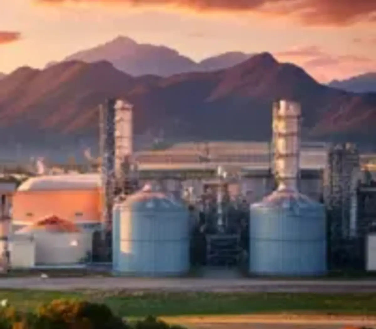 Industrial facilities against a sunset backdrop, highlighting investment opportunities in energy.