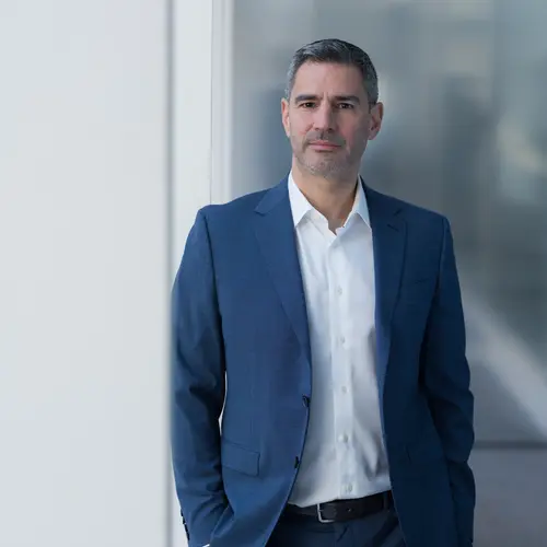 An asset manager in formal attire stands confidently in Amundi offices.