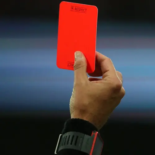 Red card held up in a sports setting, symbolizing penalty and decisive action.