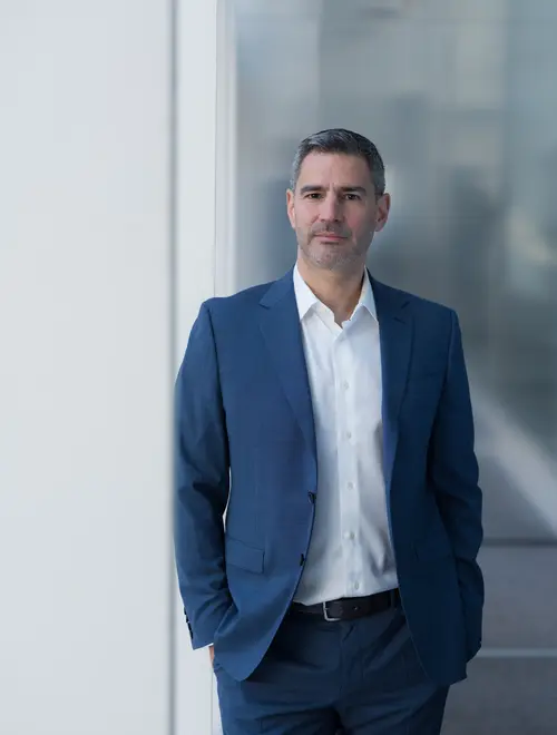 An asset manager in formal attire stands confidently in Amundi offices.