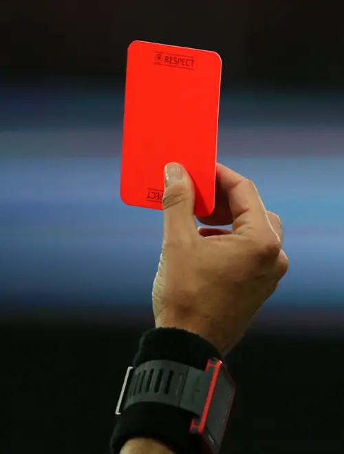 Red card held up in a sports setting, symbolizing penalty and decisive action.