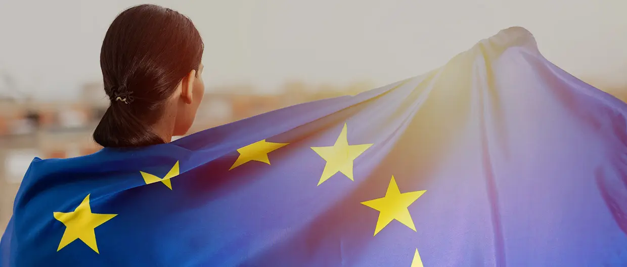 A woman wrapped in the European Union flag and looking towards the sunset