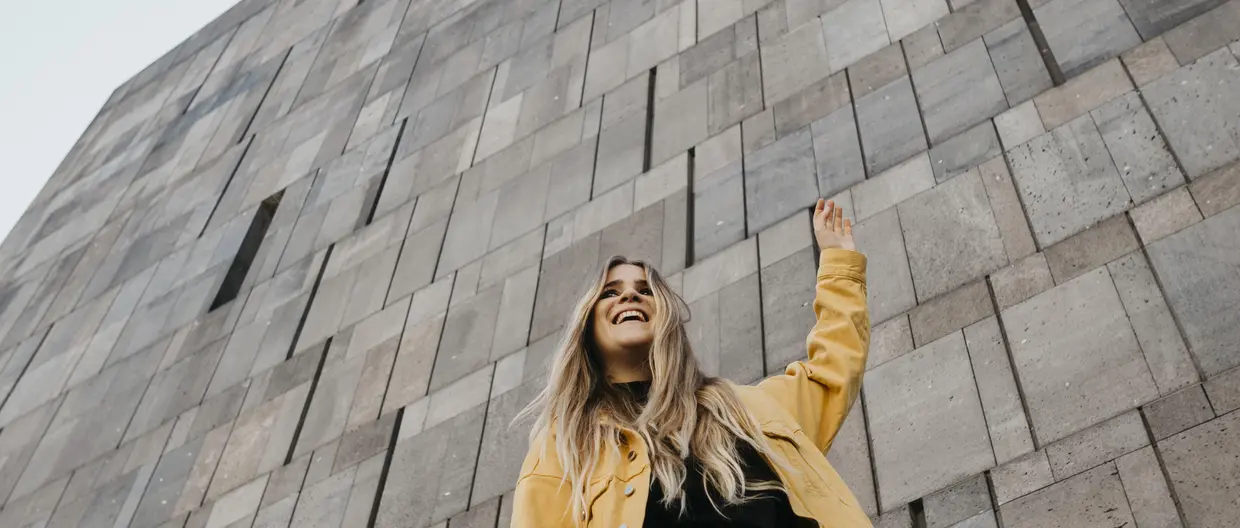 Woman in yellow jacket in front of wall