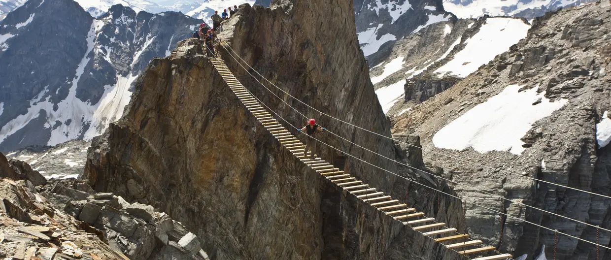 Hiker on wood bridge in between mountains