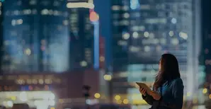 immagine di una ragazza con un tablet in mano su sfondo skyline notturno