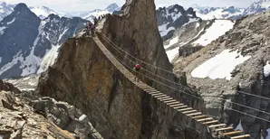 Hiker on wood bridge in between mountains