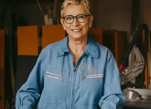 Woman in overalls standing over plans