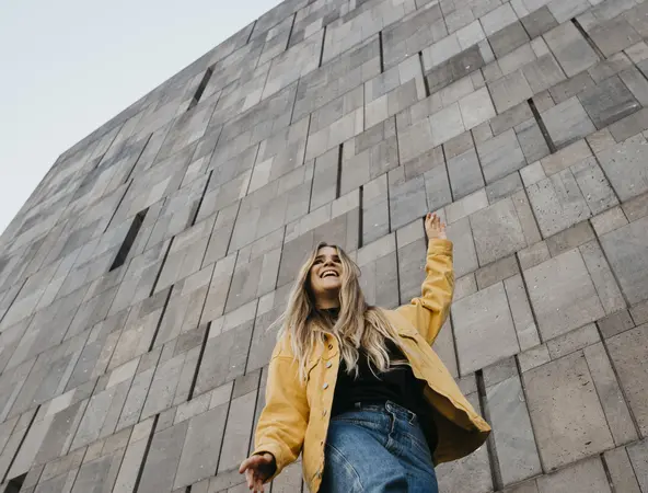 Woman in yellow jacket in front of wall